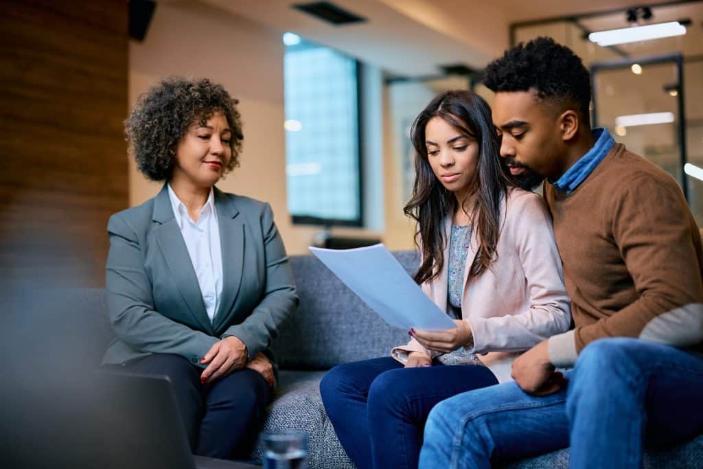 Three professionals in a modern office setting, reviewing a document about myths and misconceptions of probate together on a couch.
